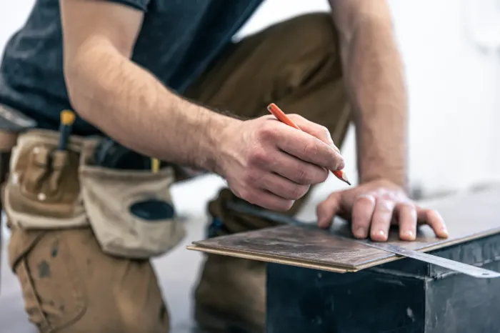 Artisan posant du carrelage imitation bois dans une habitation