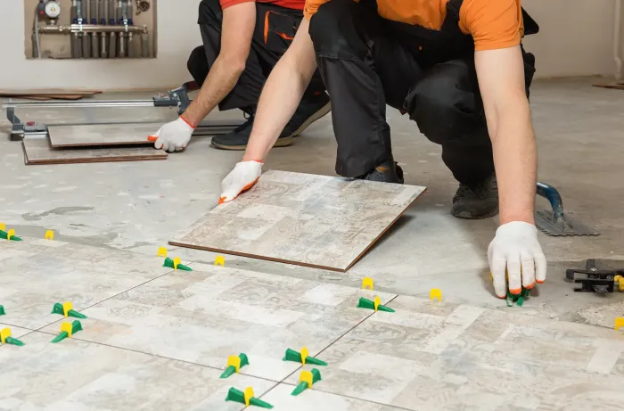 Artisans posant avec soin du carrelage grand format sur un chantier