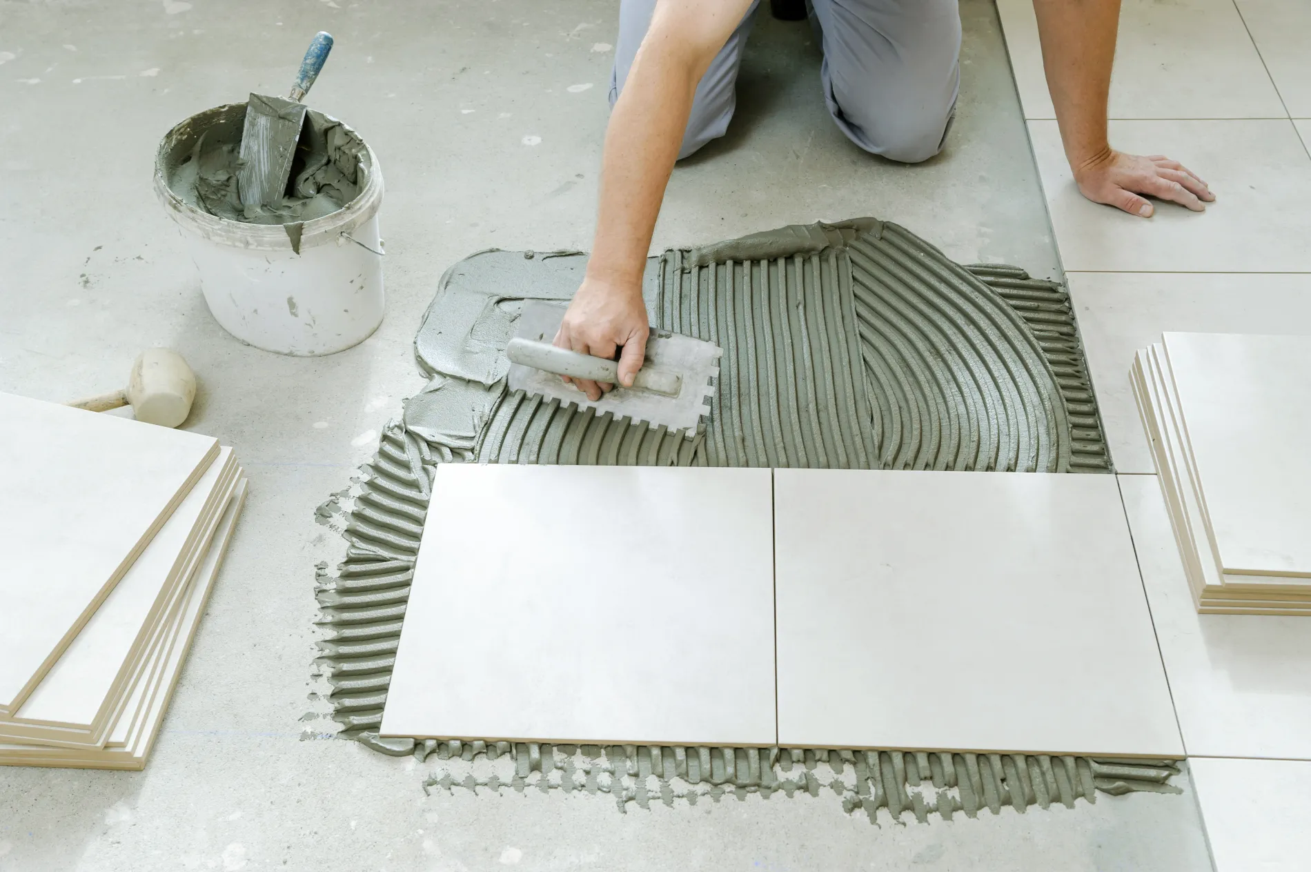 Artisan utilisant une spatule crantée pour la pose de carrelage